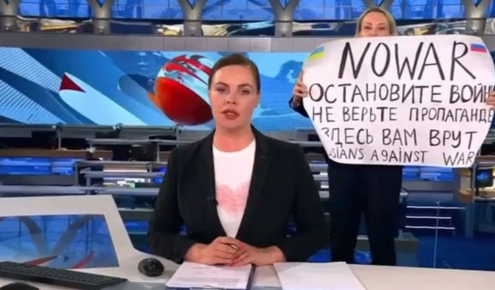 Marina Ovsyannikova carrying a poster behind the news anchor, Ekaterina Andreeva